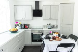 a kitchen with white cabinets and a table with fruit on it at Entire family home , large rear garden and free parking in Belfast