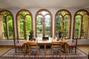 ein Esszimmer mit einem Tisch, Stühlen und Fenstern in der Unterkunft Maison Suchard, tradition & elegance in the Jura in Couvet