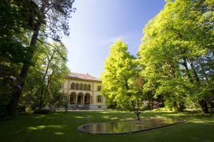 a building in the middle of a yard with trees at Maison Suchard, tradition & elegance in the Jura in Couvet