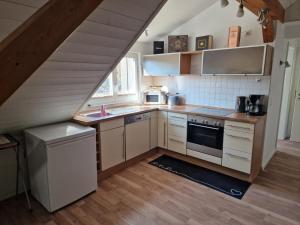 eine Küche mit weißen Schränken, einer Spüle und einer Treppe in der Unterkunft Dachstudio Eggingen in Eggingen
