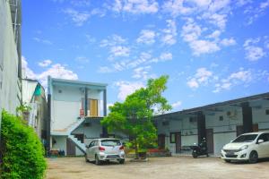 諫義里的住宿－HP Residence Mitra RedDoorz near Alun Alun Kediri，两辆汽车停在大楼前的停车场