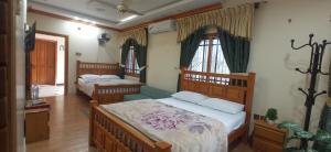 a bedroom with two beds and a couch at Eagle Nest Cottage Muzaffarabad by LMC in Muzaffarabad