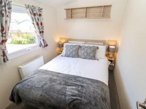 um pequeno quarto com uma cama e uma janela em 3 Bed New Lodge - 7 Lakes Country Park DN17 em Scunthorpe