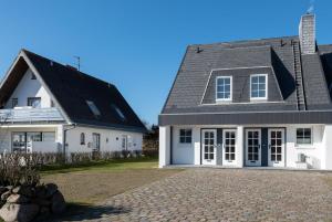een wit huis met een grijs dak en een oprit bij Haus Dünenrand, App 2 in Wenningstedt