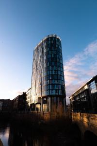 wysoki szklany budynek obok rzeki w obiekcie Apartment @ I Quarter w Sheffield