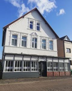 a white building with windows on a street at Pension Kapitän Schmuck in Borkum