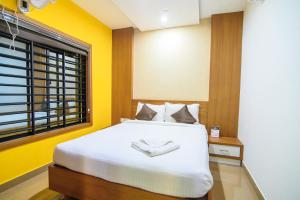 a bedroom with a white bed with yellow walls and a window at Rinad Castle Vythiri By Hamra Retreat in Vythiri