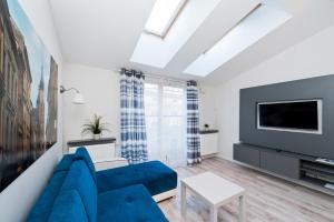 uma sala de estar com um sofá azul e uma televisão em Apartamenty Sun & Snow Kraków Browar Lubicz na Cracóvia