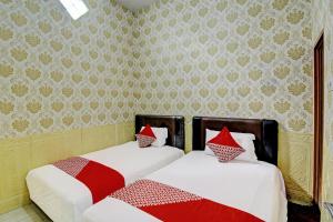 dos camas sentadas una al lado de la otra en un dormitorio en OYO Life 92312 A+ Cozy Rooms Syariah, en Kediri
