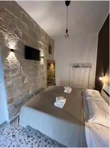1 dormitorio con 1 cama grande y pared de piedra en La PortaVecchia - #Home, en Monopoli