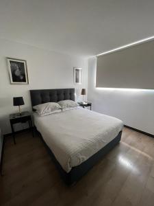 a bedroom with a large bed and two tables with lamps at 24 metros Clínica las Condes in Santiago
