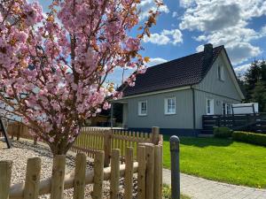 a fence in front of a house with a flowering tree at Landurlaub in Schmallenberg Landhäuschen in Schmallenberg