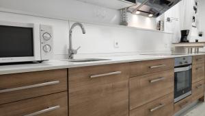 a kitchen with wooden cabinets and a sink and a microwave at Estudio HortaBCN in Barcelona