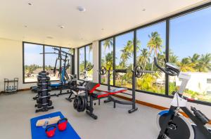 a gym with treadmills and cardio equipment and windows at TOA Hotel & Spa Zanzibar in Pongwe