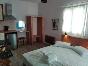 a bedroom with a white bed and a kitchen at Amorgaia 2 in Katapola