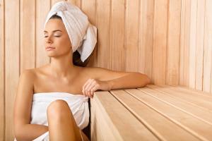 a woman sitting in a sauna with a towel on her head at Crowne Plaza Dubai Deira, an IHG Hotel in Dubai