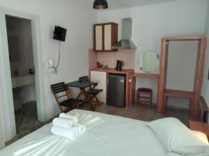 a bedroom with a white bed and a kitchen at Amorgaia 2 in Katapola