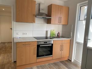 a kitchen with wooden cabinets and a stove top oven at Tempel-inn Appartements Molkereistr. 2 in Werlte