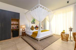 1 dormitorio con 1 cama blanca con dosel en TOA Hotel & Spa Zanzibar en Pongwe