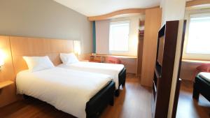 een hotelkamer met 2 bedden en een televisie bij ibis Vitré Centre in Vitré