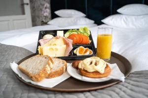 グダニスクにあるBrowar Hevelius Apartmentsの朝食用の食品とオレンジジュースのトレイ