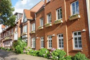 um edifício de tijolos vermelhos com janelas e caixas de flores em Hotel Osterkrug em Husum