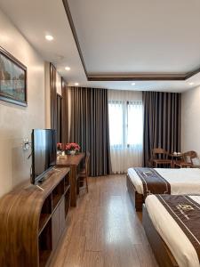 a hotel room with two beds and a flat screen tv at Linh Trang Hạ Long Hotel in Ha Long