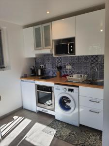 a kitchen with a washing machine and a microwave at Appartement Pérols Centre in Pérols