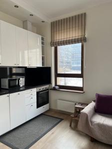 una cucina con armadi bianchi, un divano e una finestra di Apartment Vilnius Old Town a Vilnius