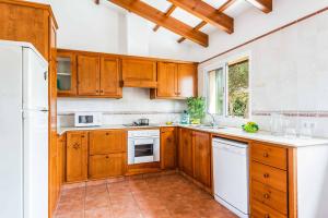 uma cozinha com armários de madeira e electrodomésticos brancos em Villa Flomertor 2 em Cala en Blanes