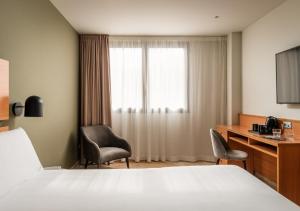 タラゴナにあるHotel SB Express Tarragonaのベッド、デスク、窓が備わるホテルルームです。