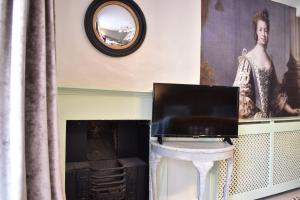 a television sitting on a table next to a fireplace at Davenford Cotswold Gardens in Stow on the Wold