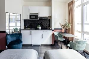 una cucina con armadi bianchi, tavolo e sedie di Hey - Aparthotel Brussels a Bruxelles