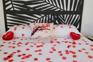 a bed with red rose petals on it at Villa piscine balnéothérapie entièrement privée in Barras