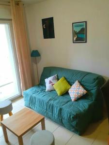 uma sala de estar com um sofá verde e uma mesa em Appartement cozy pour curistes et touristes em Salies-de-Béarn