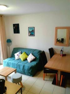 uma sala de estar com um sofá azul e uma mesa em Appartement cozy pour curistes et touristes em Salies-de-Béarn