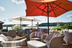 un patio con sillas, sombrillas y una masa de agua en Hôtel du Golf de l'Ailette, The Originals Relais (Qualys-Hotel) en Chamouille