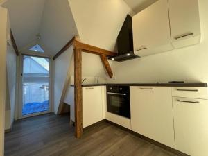 an attic kitchen with white cabinets and a window at Das Herzchen von Ellenz in Ellenz-Poltersdorf