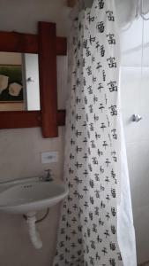 baño con lavabo y cortina de ducha con jeroglíficos en Pousadinha Ateliê da Maite, en Paraty