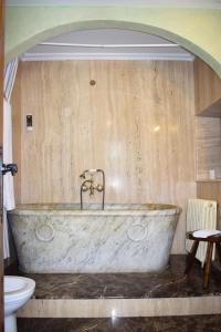 uma grande banheira de pedra na casa de banho com WC em Habitaciones Casona De Linares em Selaya
