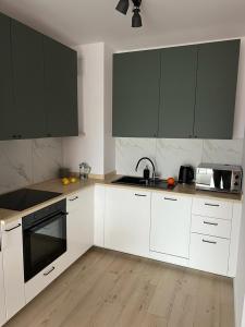 a kitchen with white cabinets and black appliances at Apartamenty Akademicka przy Onkologii 2 in Bydgoszcz