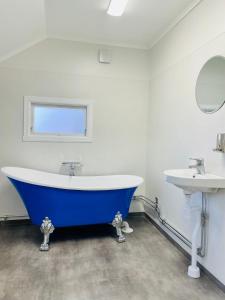La salle de bains est pourvue d'une grande baignoire bleue et d'un lavabo. dans l'établissement Lilla Röda Huset., à Sjötofta