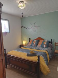 a bedroom with a bed with a blue and yellow comforter at une pause quelque part au jardin des érables et des niwakis in Saint-Médard-de-Guizières