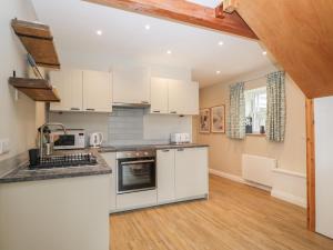a kitchen with white cabinets and a wooden floor at The Old Haberdashery in Swanage