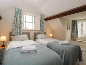 two beds in a room with two windows at The Old Haberdashery in Swanage