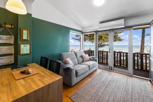 a living room with a couch and views of the ocean at Rawsons shack Beachfront unit suits single or couple in Henley Beach South