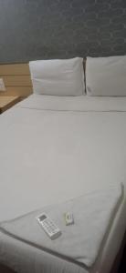 Una cama blanca con mando a distancia. en RAAJ PEARL, en Chennai