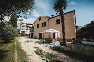 a house with a palm tree and a white umbrella at New renovated appartment Mauri in Poreč