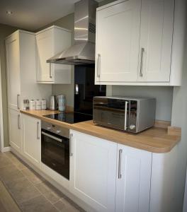 a kitchen with white cabinets and a microwave at 3-bedroom bungalow, central Ambleside with parking in Ambleside