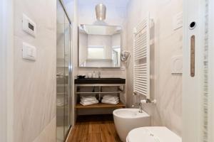 La salle de bains blanche est pourvue d'un lavabo et de toilettes. dans l'établissement La finestra sul canale, à Bologne